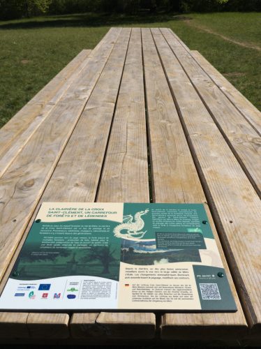 Une grande table en bois a été installée au cœur de la clairière. Autour d’elle, des plantations de jeunes essences locales ont été réalisées avec les élèves de l’école primaire afin de diversifier les espèces présentes sur le site. Les visiteurs pourront également découvrir le kiosque en pierre, réaménagé à l’occasion de ces travaux pour offrir un espace plus accueillant. © PnrL